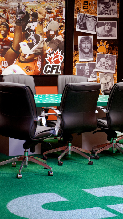 The BC Lions conference room features a table painted like a CFL football field, life-sized photos of Grey Cup winners and assorted team legends, and — wait for it — actual Astroturf flooring painted like centre field. Photo by Jason Kurylo for Pucked in the Head.