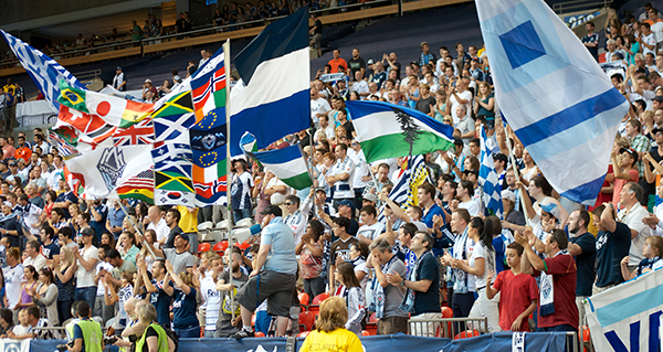 Zach Meisenheimer (in front, with bullhorn) leads the Curva Collective in game-long chants and dances. Exactly this sort of passionate fandom led to several Whitecaps fans being asked leave a Canucks game last season. Photo by Jason Kurylo for Pucked in the Head.