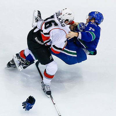 Michael Ferland of the Abbotsford Heat knocks Utica Comets defenseman Kent Huskins off his feet with a single punch in AHL action. Clint Trahan photo courtesy of the Abbotsford Heat.