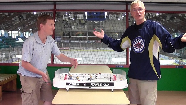 Hockey Night in Canada icon Jim Hughson schools Pucked in the Head founder Jason Kurylo in table hockey and microphone etiquette. Photo by Andrew Delbaere for Pucked in the Head.