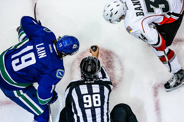 Vancouver Canucks prospect Kellen Lain and Calgary Flames property Carter Bancks line up for a face-off in AHL action. Clint Trahan photo courtesy of the Abbotsford Heat.